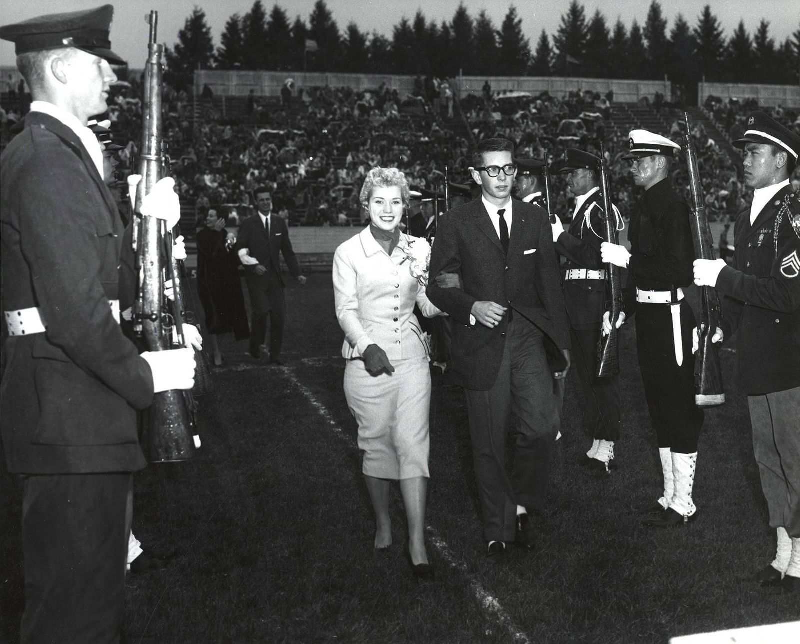 Homecoming queen, Charmaine Deitz, being escorted across football field in the Homecoming game