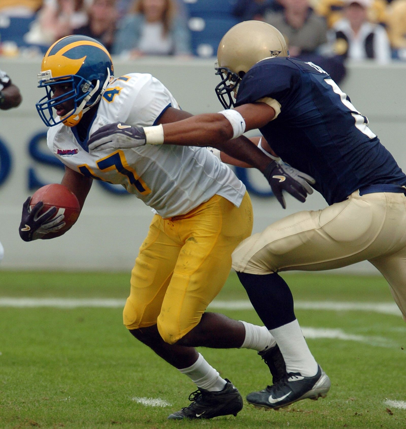 U.S. Naval Academy slot back Frank Divis reaches to bat the ball out of Delaware Blue Hens defensive back Sidney Haugabrook's hand.