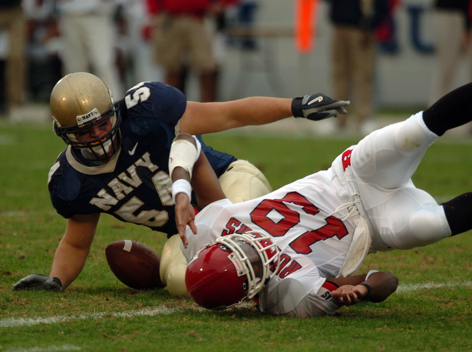 U.S. Naval Academy Midshipman 1st Class Adam Horne rolls out of the play after causing Rutgers University (4-5) Terrance Shawell to fumble.