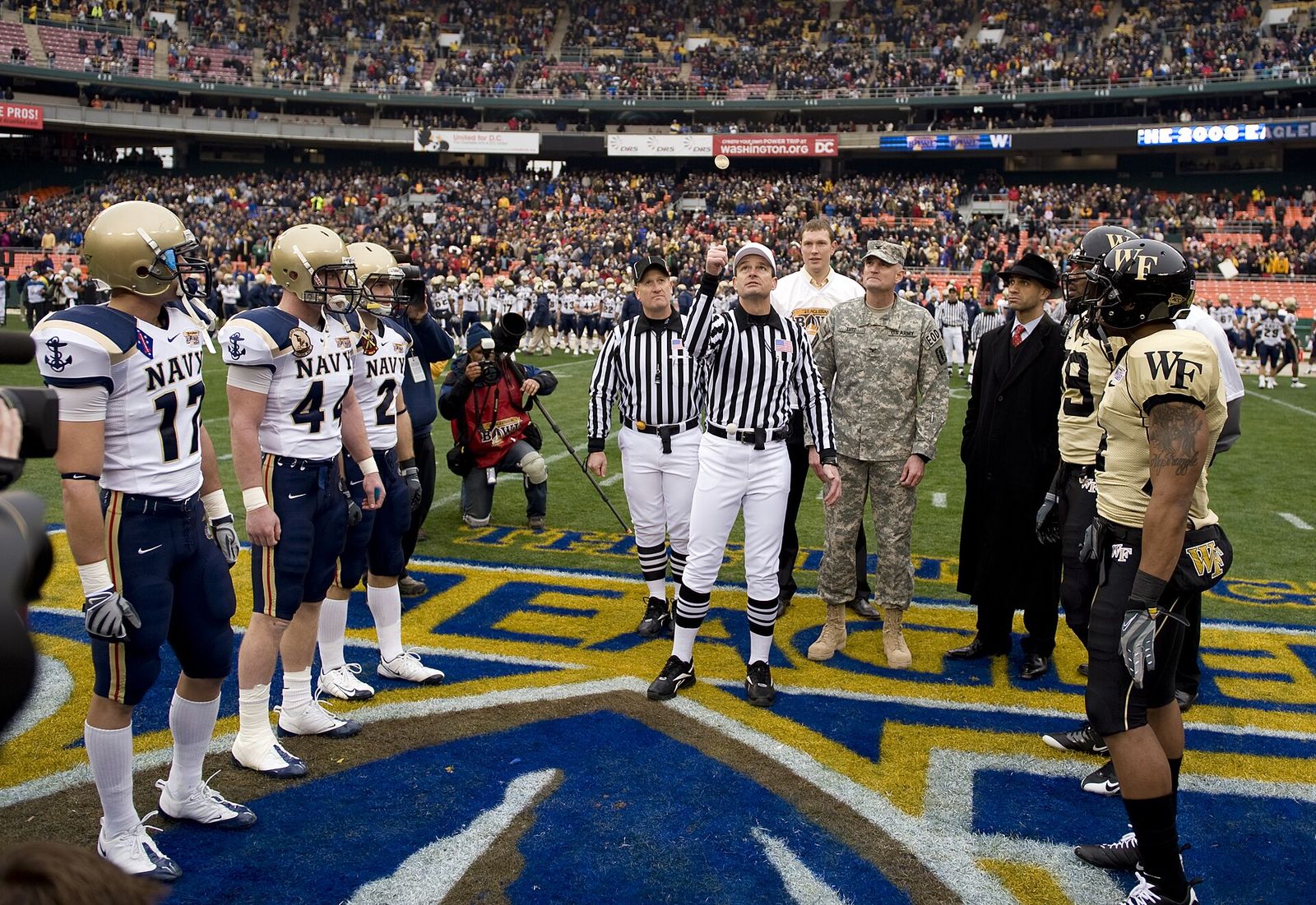 The referee conducts the ceremonial coin toss before the inaugural Eagle Bank Bowl between the Navy Midshipmen and the Wake Forest Demon Deacons.