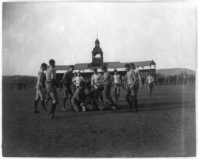 Yale Univ. football game: scrimmage; stadium with clock tower in backgorund