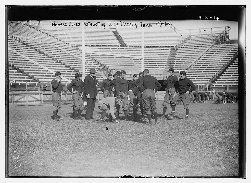 Howard Jones instructing Yale Varsity football team on playing field, New York